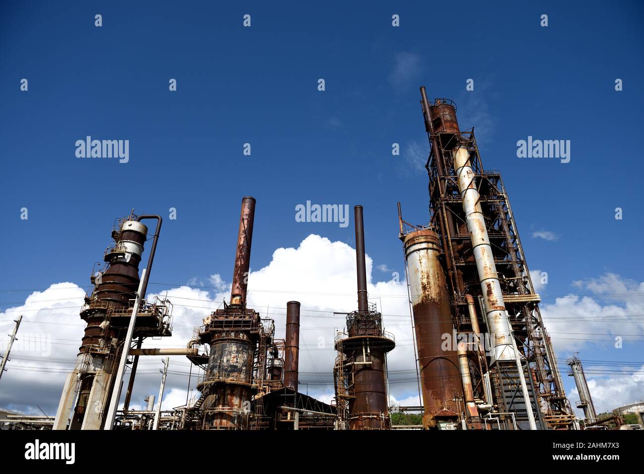 Industrielle Petrochemie-Anlage, rostig verwitterte Industrieanlage mit Rohren, Tanks, Schornsteinen und blauem Himmel und Wolken, in Puerto Rico Stockfoto