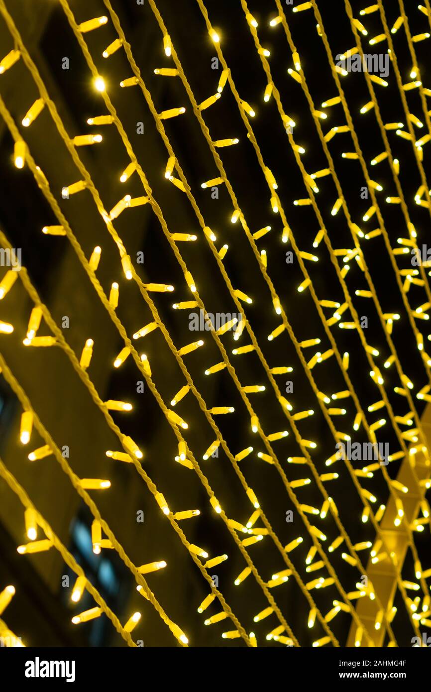 Eine festliche Girlande mit gelben Lichter in einem großen Plan leuchtet in der Dunkelheit vor dem Hintergrund der Gebäude. Farbenfroh und zauberhafte Dekoration für Th Stockfoto