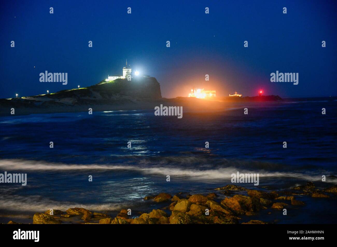 Nobbys Head und Strand mit Leuchtturm und Schiff den Hafen verlassen Stockfoto