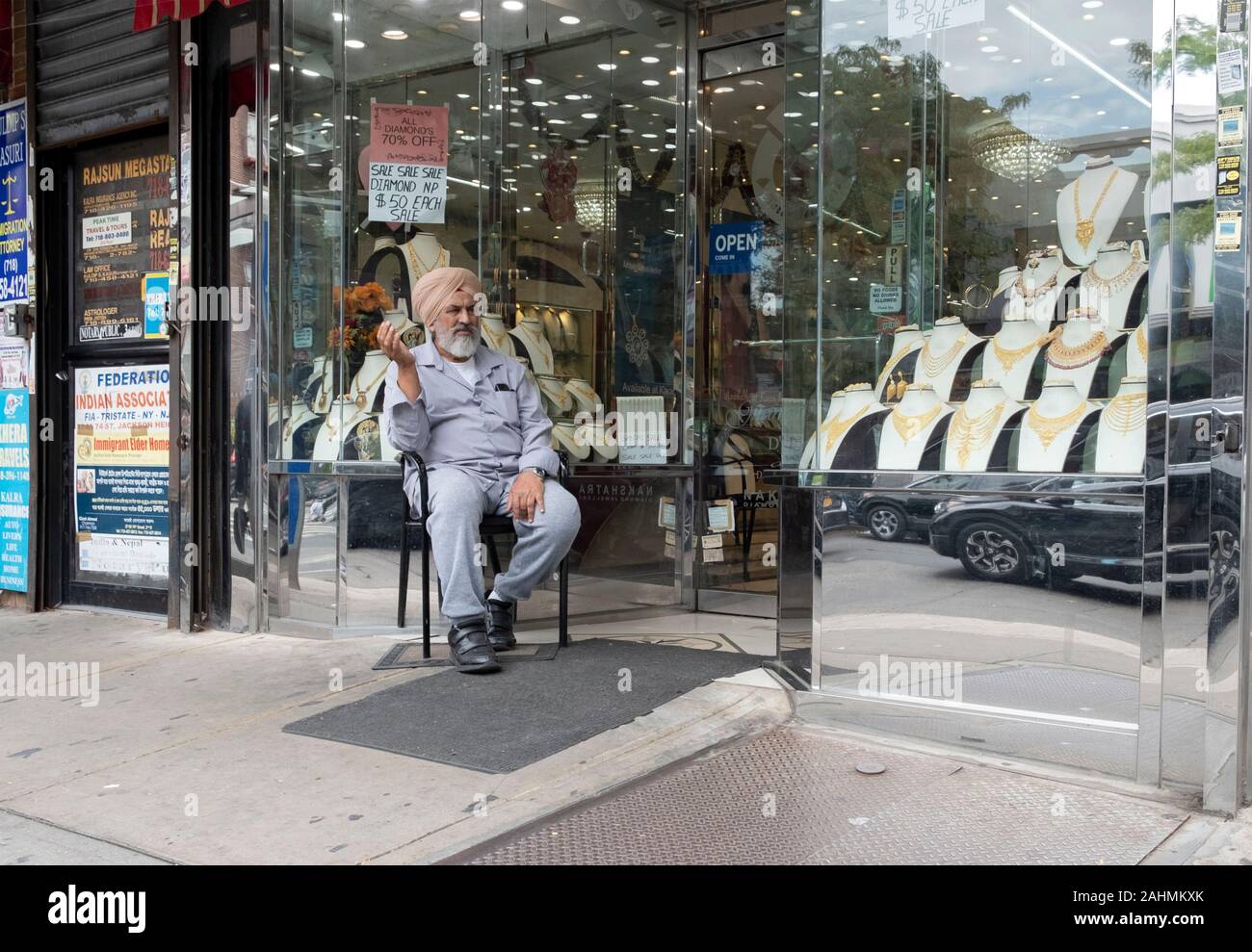 An einem warmen Tag, fallen einem Sikh Juwelier sitzt vor seinem Geschäft allein in seinen Gedanken. Auf 74th Street in Jackson Heights, Queens, New York City. Stockfoto