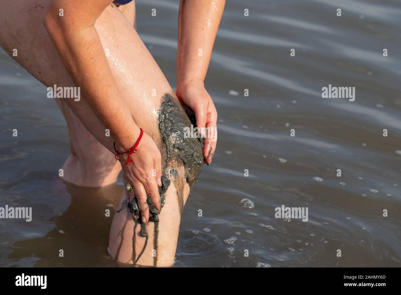 Frau Anwendung auf ihrem Körper Knie salzig Heilschlamm in See Stockfoto