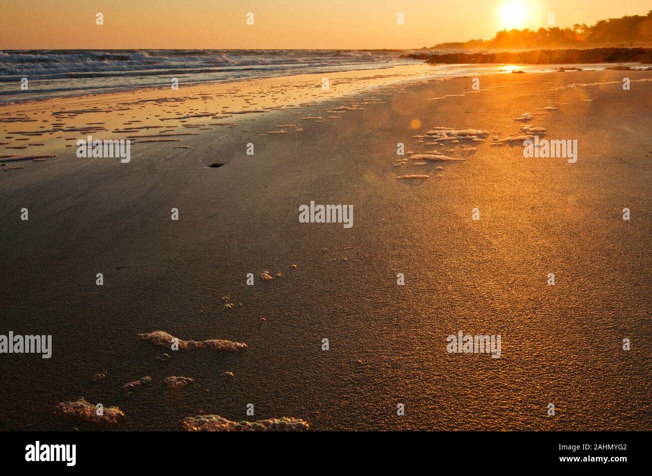 Sonnenaufgang über den Atlantik und die Insel Yeu Horizont, die Sonne ist die Färbung der nasse Sand des Strandes in goldenen Farben, Stücke Schaumstoff sind folgenden Th Stockfoto