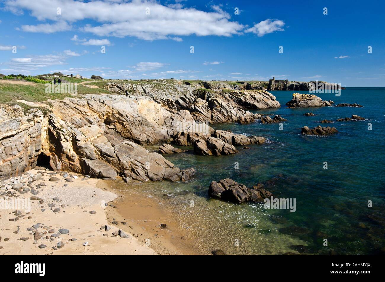 Felsige Küste im Süden der Insel Yeu, den Sandstrand und transparentem Wasser stehen im Vordergrund und die Ruinen der alten Burg bei fare Hintergrund. Frankreich, Ve Stockfoto