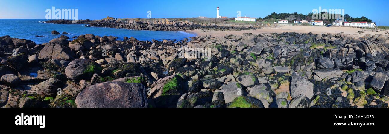 Küste Steine im Osten der Insel Yeu mit Sand umgeben und der Leuchtturm am Pointe des Corbeaux im Hintergrund ist Stockfoto