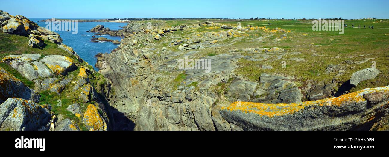 Panorama des Wilden felsigen Küste im Südosten der Insel Yeu mit strukturierter Steine im Vordergrund, grüne Ebene mit Walking Pass und Menschen ist auf der rechten Seite Stockfoto