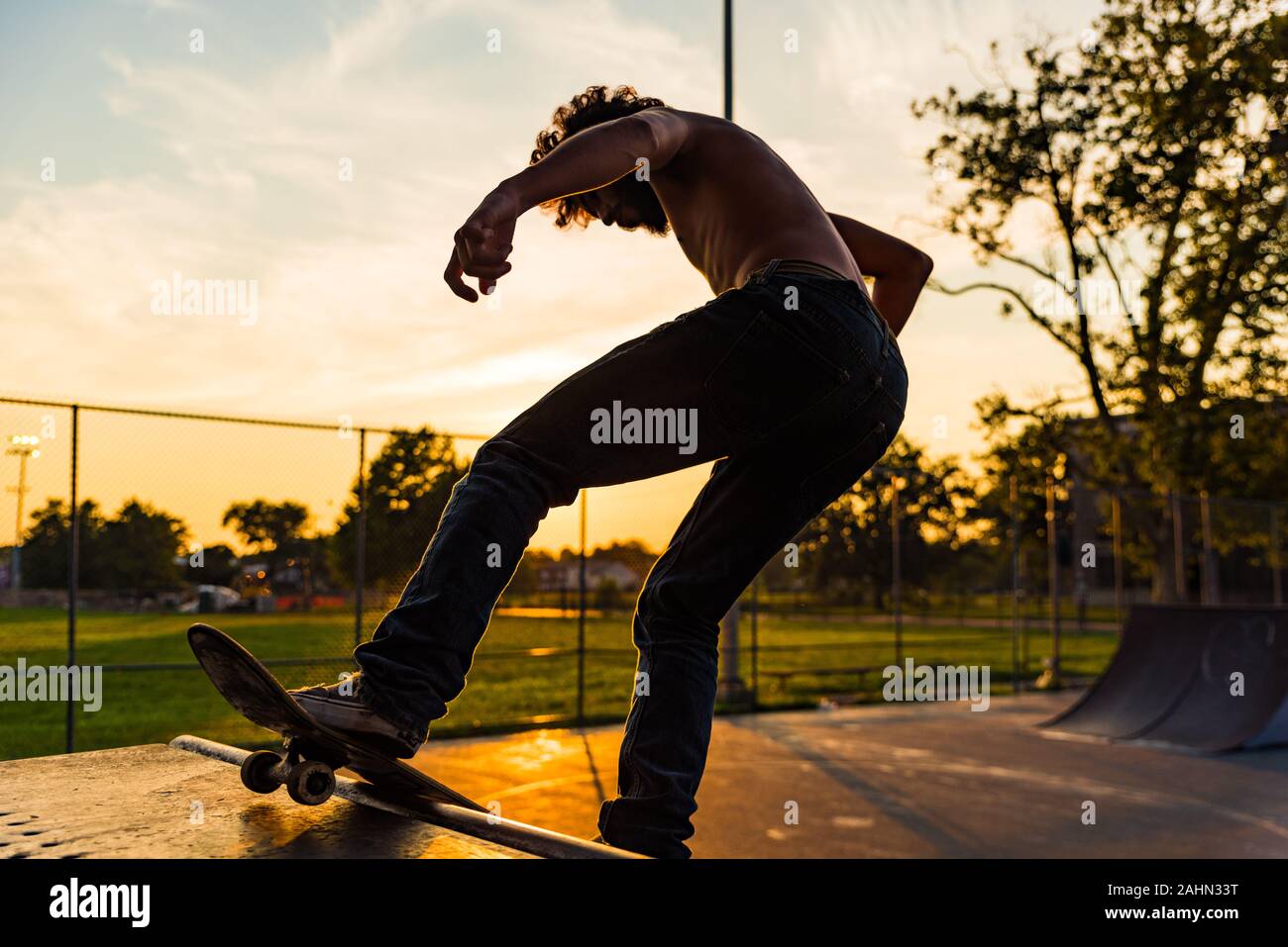 Ein junger Mann der Skate Tricks auf ein Viertel Rohr in einem urbanen Skate Park während der Goldenen Stunde. Stockfoto Ein junger Mann der Skate Tricks auf ein Viertel Rohr in einem urbanen Skate Park während der Goldenen Stunde. Stockfoto