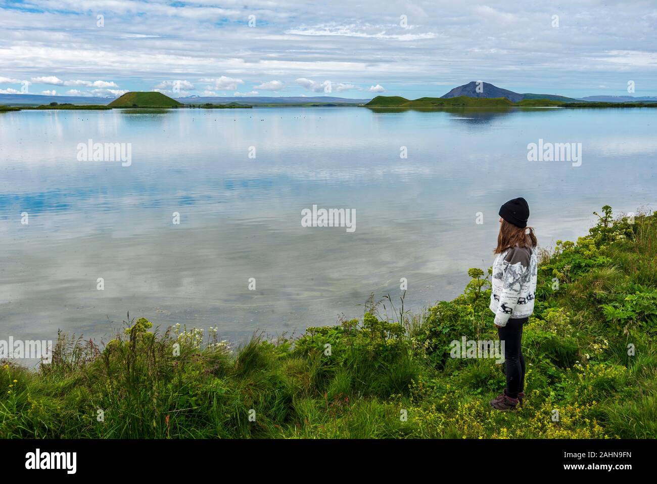 Mädchen Teenager ist der Aufenthalt in der Grenze von Myvatn See im Norden von Island. Inseln vulkanischen pseudo Krater sind im Hintergrund. Stockfoto