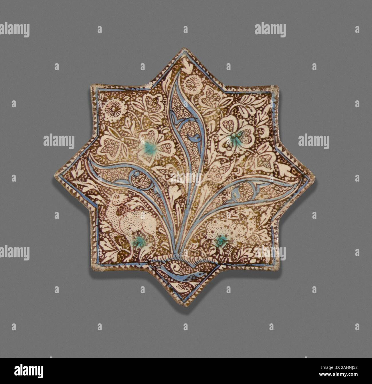 Islamische. Star-Shaped Fliese. 1201 - 1300. Iran. Fritware in Blau und Türkis in ein lichtundurchlässiges Weiß lackiert Glasur, mit Glanz über die Glasur Glanz bemalte Keramik waren populär im Iran vor dem Einfall der Mongolen im 13. Jahrhundert. Die Technik weiter unter Mongolische Regel populär zu sein, das häufig die gleichen Formen und Muster als früheren Glanz Keramik. Zusätzliche Farbe in den Kobalt- und Türkis Unterglasurmalerei, welche Elemente in der Gestaltung wie der dreiteilige Anlage im Zentrum dieser Fliesen verschönert. Die Präsenz der Figurenschmuck auf diese Fliese zeigt an, dass es adorne Stockfoto