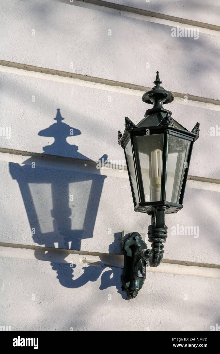 Eine Laterne in die Sonne wirft einen Schatten auf eine weiße Wand Stockfoto