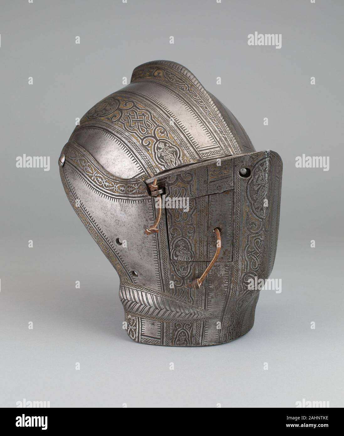 Teile einer Jousting Helm. 1560 - 1590. Mailand. Stahl, Vergoldung, Leder und die Herstellung von Rüstung war eine hochkomplexe Aufgabe erfordert viel Geschick und Know-how. Die Sonnenblende und bevor waren Teil der Rüstung getragen im Zweikampf, eine art sportlichen Kampf zwischen Paaren von montiert Kandidaten, die versuchten, sich gegenseitig mit Lanzen zu unhorse gekämpft. Der Visor war eine bewegliche Platte am Helm befestigt, um die Fläche zu schützen, während die bevor das Kinn und Kehle zu schützen, verwendet wurde. Hier die rechte Seite des bevor ist mit einer kleinen Tür, durch die Träger für zusätzliche ventilatio geöffnet werden konnte ausgestattet Stockfoto