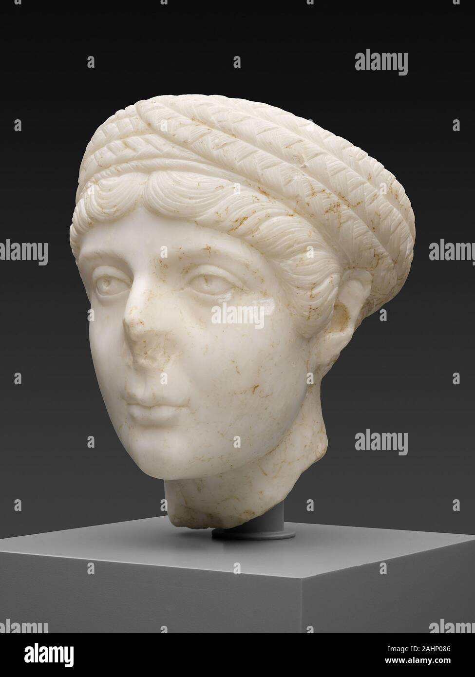 Antike römische. Portrait Kopf einer jungen Frau. 130 AD - 140 AD. Römische Reich. Marmor Dieses elegante Portrait ist das absichtliche Bildnis einer jungen Frau in den frühen 20er Jahren, die einen zarten Stirn hatte, hohe Wangenknochen, große Augen, eine bogenförmige Mund, und ein prominentes Kinn. Ihre lange Locken sind in eine kunstvolle Frisur arrangiert, modische zu verschiedenen Zeiten während der Kaiserzeit, in der die Haare in der Mitte getrennt war, in Wellen über die Stirn gekämmt, und geflochtene in Zöpfen, die kunstvoll um den Kopf, wie ein Turban eingewickelt waren. Abgebrochen am Hals, Es war einmal Teil eines größeren Stockfoto