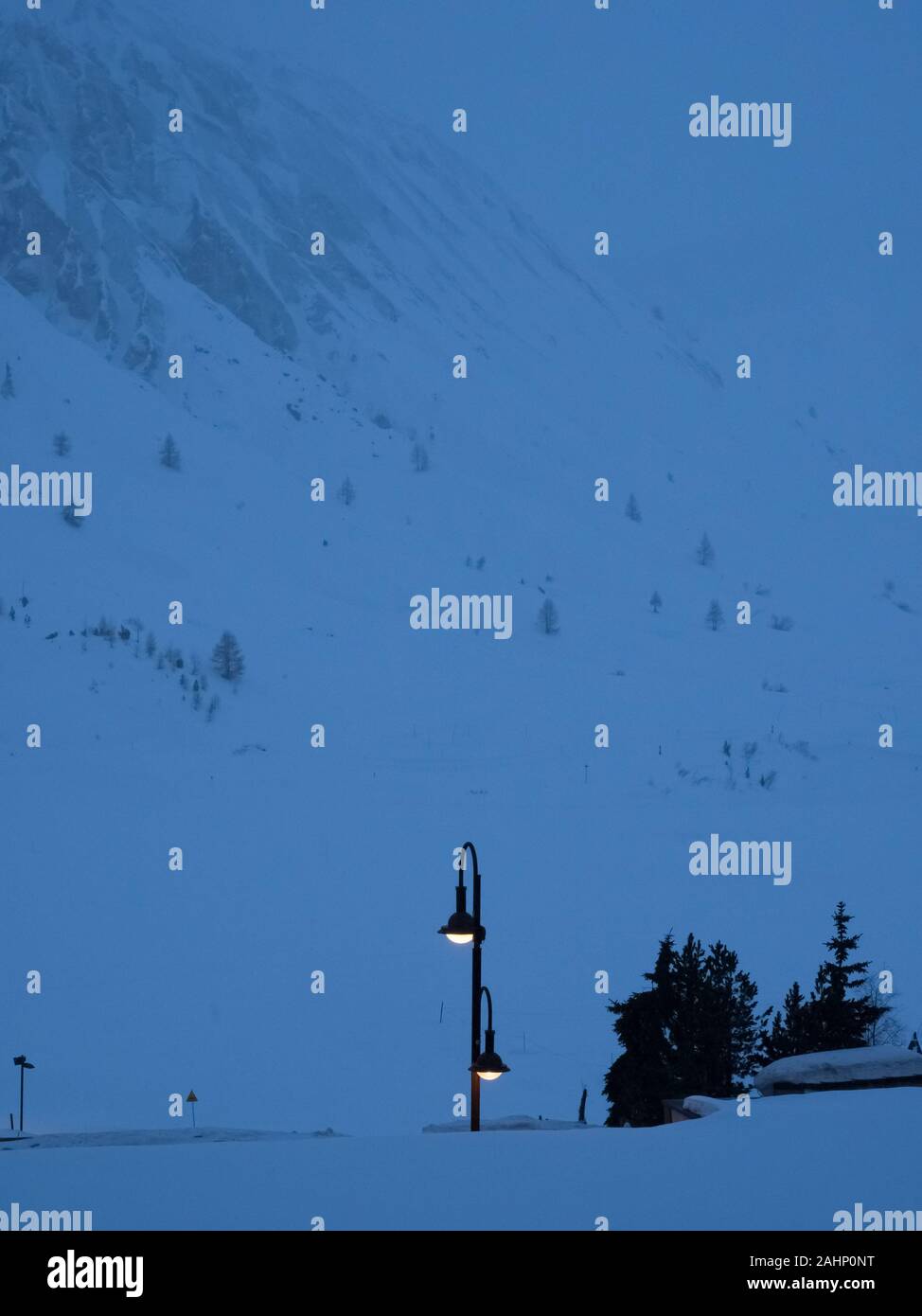 Leuchtet eine Lampe leuchtet in der Dämmerung mit Schnee berg Hintergrund silhouette Bäume Tignes Stockfoto