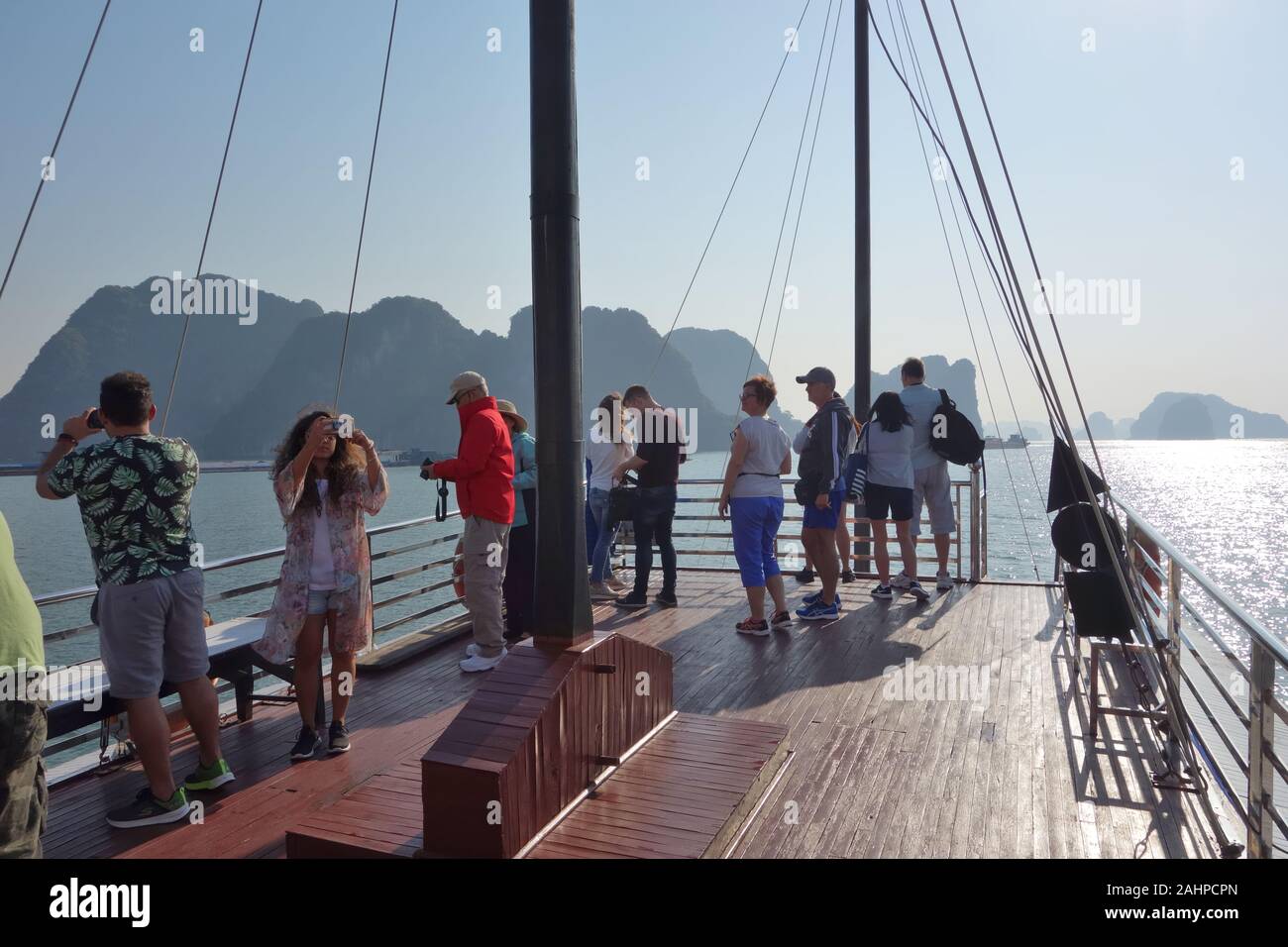 Touristen genießen die Aussicht vom Deck eines chinesischen Dschunke navigieren die Inseln Hạ Long Bay, quảng Ninh, Vietnam Stockfoto