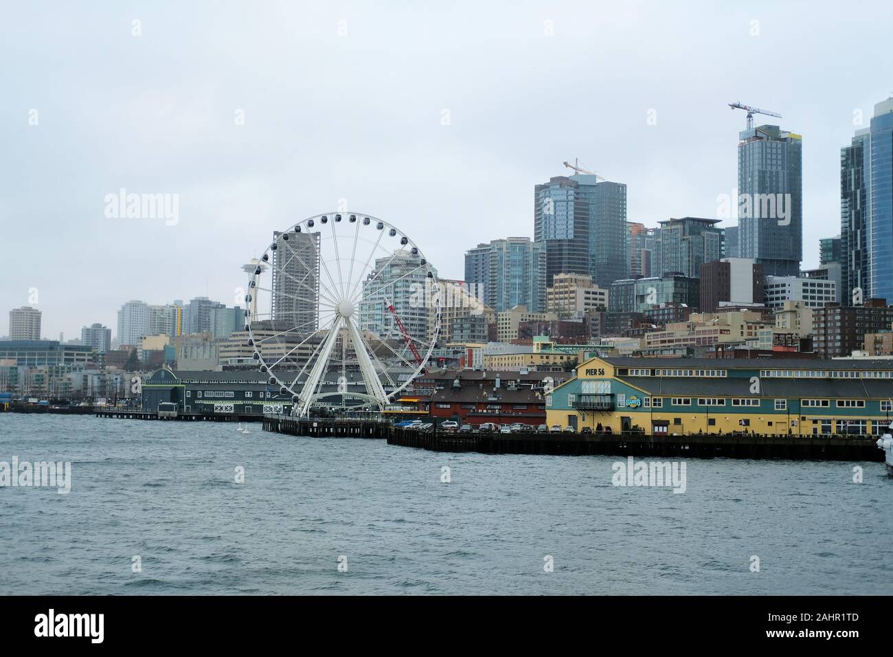 Blick auf die Innenstadt von Seattle, Washington Skyline von einem Fährschiff auf Elliot Bay; Seattle große Rad am Pier 57, Pier 56, verschwommenes Space Needle. Stockfoto