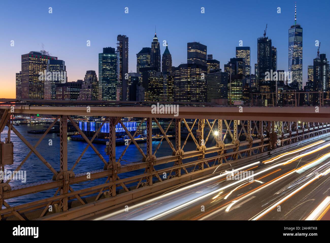 Skyline von New York von der Brooklyn Bridge bei Nacht Langzeitbelichtung Aufgenommen mit leichten Spuren von sich bewegenden Autos Stockfoto