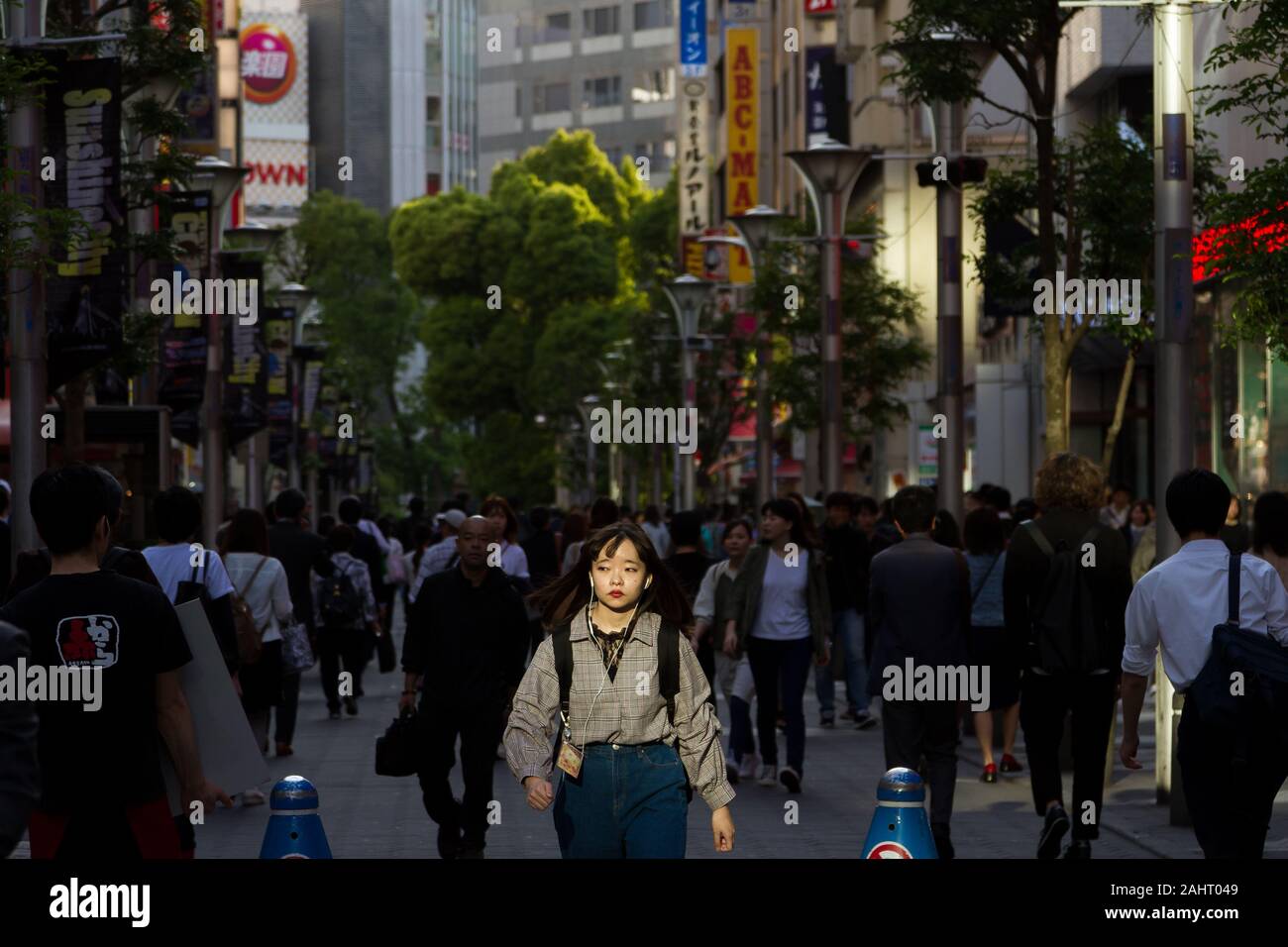 Eine junge Frau fängt das Licht ein, als sie durch die Straßen von Ikebukuro, Tokio, Japan, geht. Stockfoto