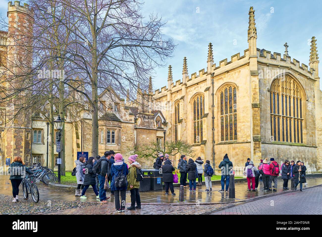 Chinesische Touristen stehen in der Nähe von Newton's apple tree Neben der Kapelle am Trinity College der Universität Cambridge, England, auf einer sonnigen und nassen Winter Tag Stockfoto