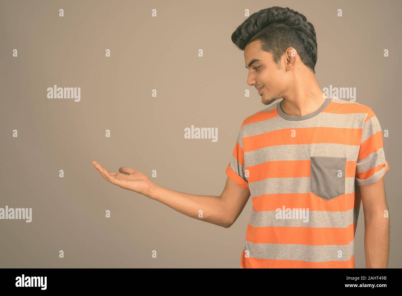 Studio shot junger indischer Mann gegen grauer Hintergrund Stockfoto