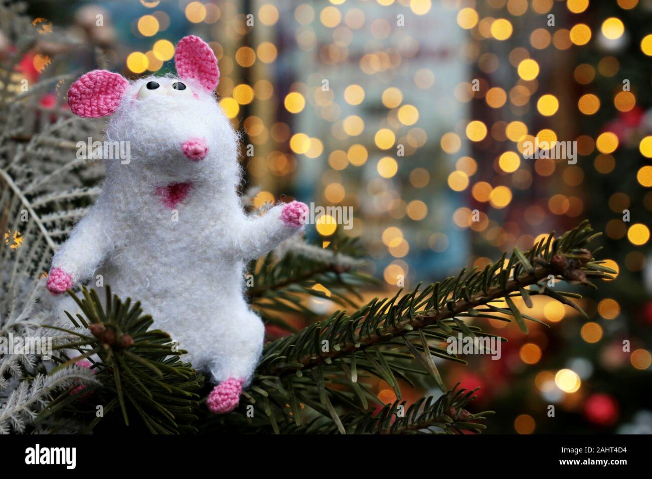 Weiß gestrickte Spielzeug Ratte auf dem Hintergrund von tannenzweigen und Golden Lights, neues Jahr. Chinesische Jahr der Ratte, Sternzeichen Symbol 2020 Stockfoto