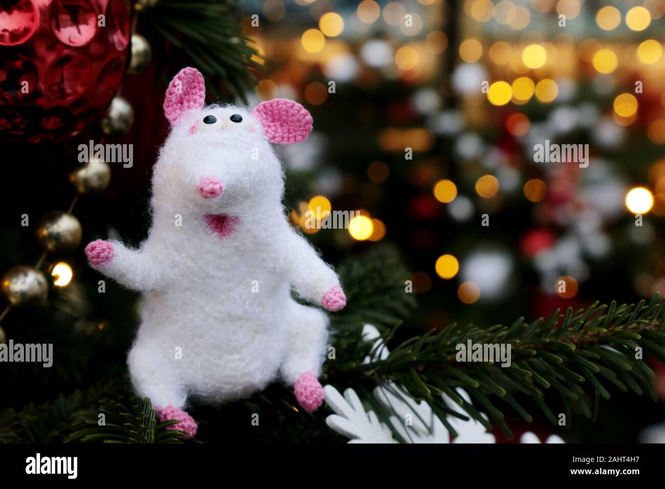 Weiß gestrickte Spielzeug Ratte auf dem Hintergrund von tannenzweigen und Golden Lights, neues Jahr. Chinesische Jahr der Ratte, Sternzeichen Symbol 2020 Stockfoto