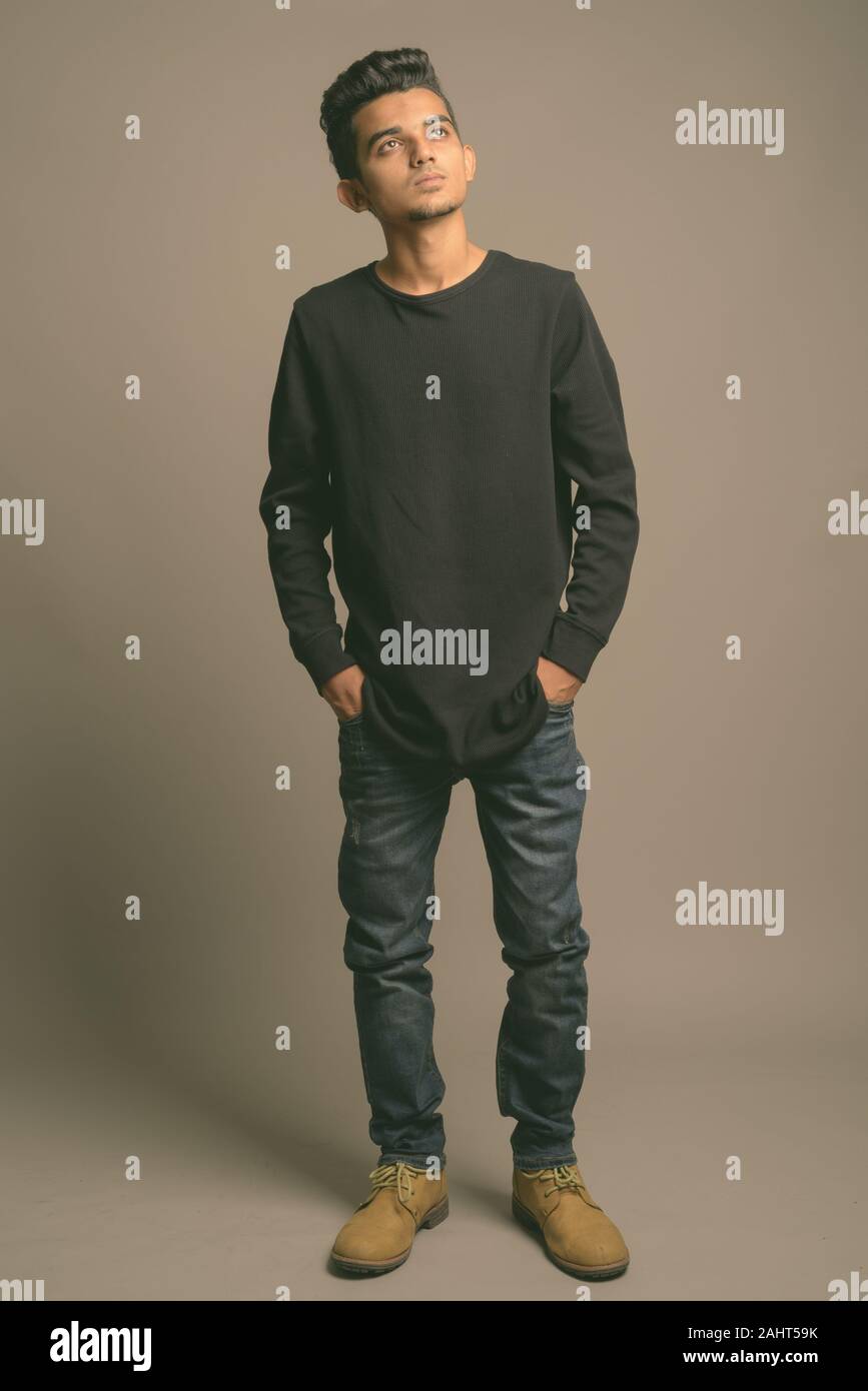 Studio shot junger indischer Mann gegen grauer Hintergrund Stockfoto