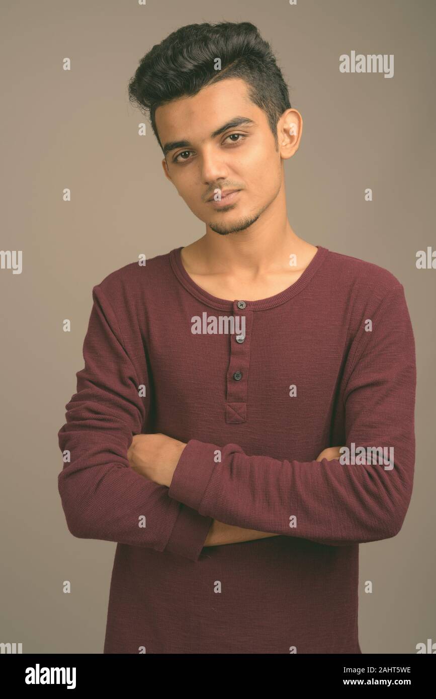 Studio shot junger indischer Mann gegen grauer Hintergrund Stockfoto