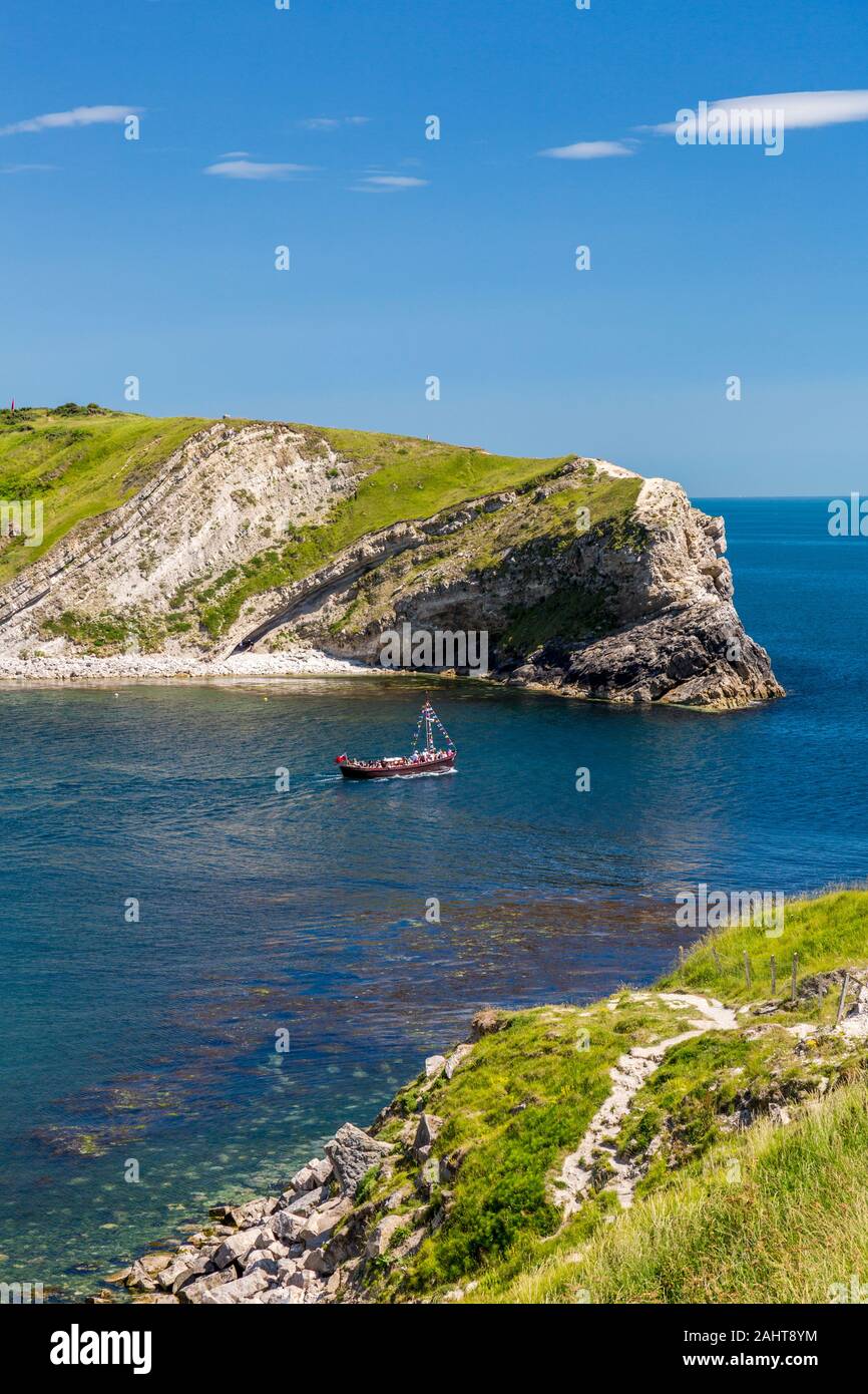 Ein Motorboot voller Urlauber Blätter Lulworth Cove für eine Tour entlang der Jurassic Heritage Coast Dorset, England, Großbritannien Stockfoto
