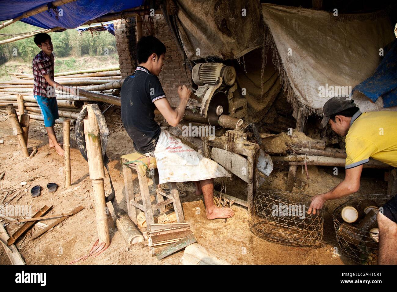 Asiatische Arbeiter schneiden mit Sägemaschine die Bambusstämme auf Größe, schließlich machen die Schöffen. Stockfoto