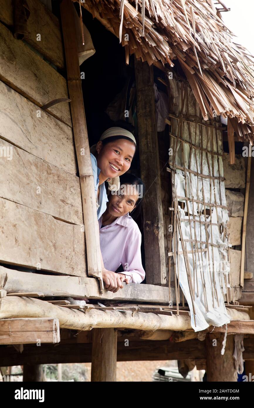 Zwei asiatische Frauen lächeln, schauen aus dem Fenster ihres Stielhauses Stockfoto