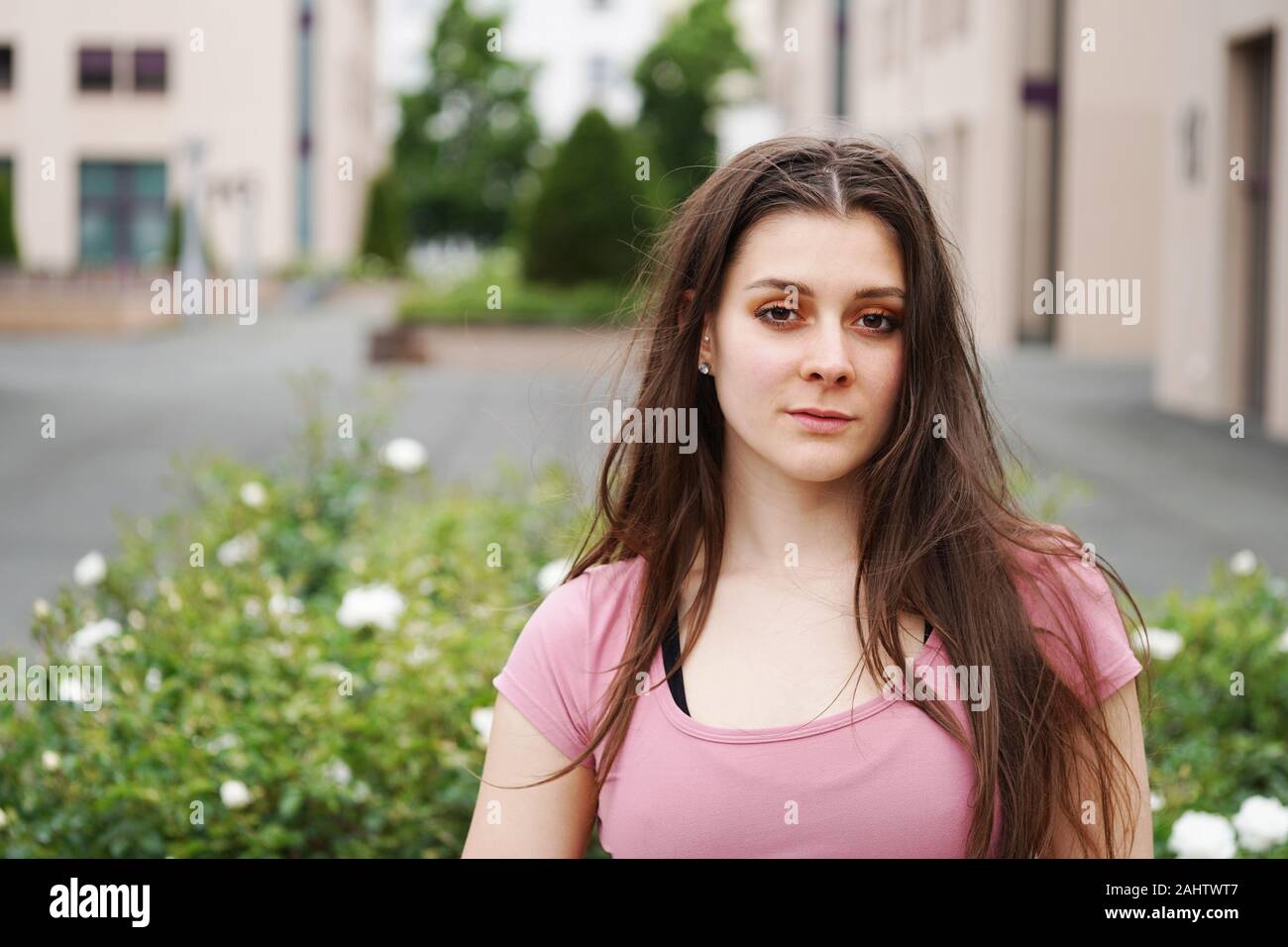Straße Porträt einer ernsthaften jungen Frau mit langen brünetten Haar outdoor. Schöne junge Frau in einem urbanen Umfeld mit Platz kopieren Stockfoto