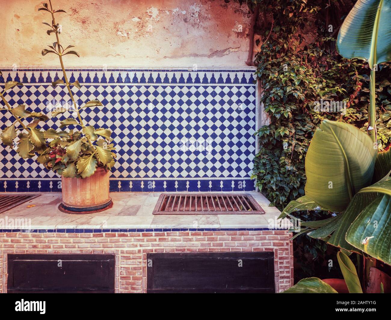 Ein Vintage Style Foto von einem marokkanischen Cooking Grill im Außenbereich Garten, mit einem traditionellen blau-weißen Fliesen Kulisse. Stockfoto