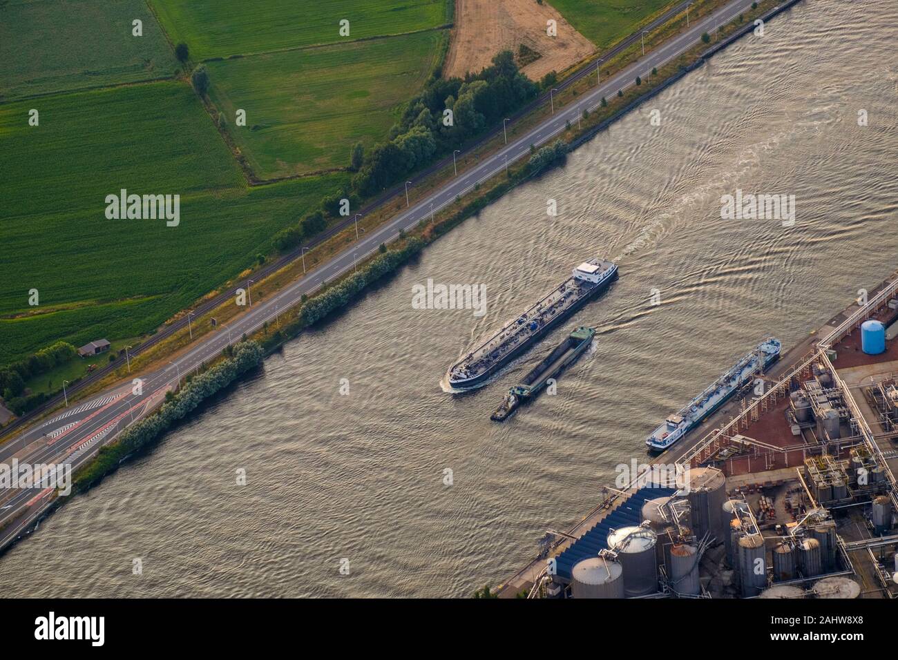 Am wichtigen Ghent-Terneuzen-Kanal kreuzen sich zwei Boote. Rechts davon befindet sich ein Stoff aus Industriechemikalien, einer der Branchen der Region. Stockfoto