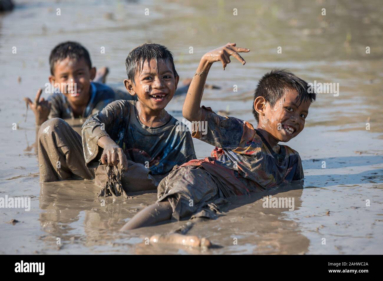 Jereweh, Indonesien - 10. September 2017: Gruppe der Kinder, die Spaß in der Pfütze von Schlamm. Stockfoto