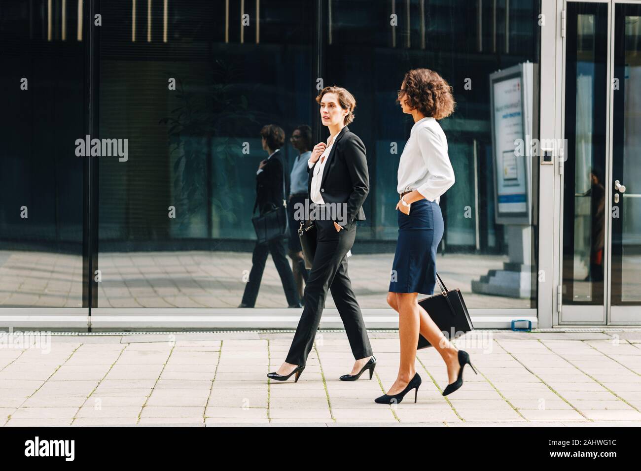 Zwei Frauen pendeln zu der in den Tag Büro Taschen. Ceo und ihre Assistentin zu Fuß auf einer Straße der Stadt. Stockfoto