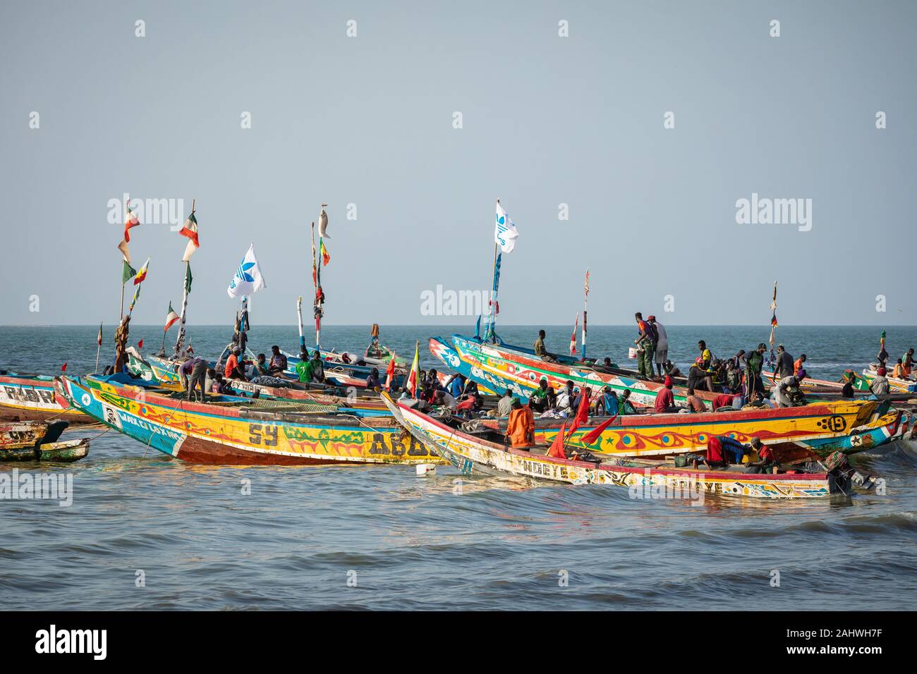 TANJI, Gambia - November 21, 2019: Szene mit Männern und Frauen, die Fische aus der Boote am Strand auf Tanji, Gambia, Westafrika. Stockfoto