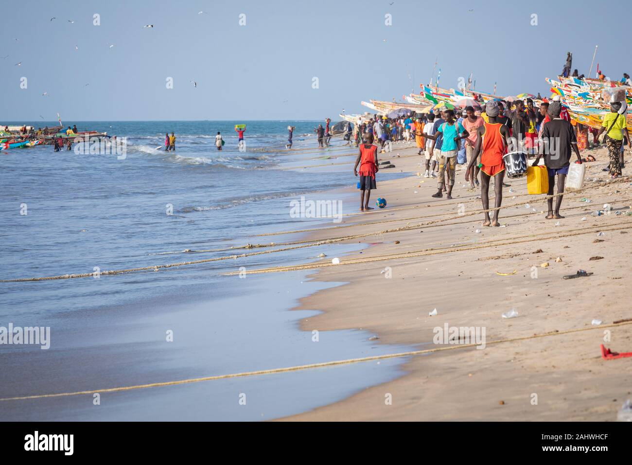 TANJI, Gambia - November 21, 2019: Szene mit Männern und Frauen, die Fische aus der Boote am Strand auf Tanji, Gambia, Westafrika. Stockfoto
