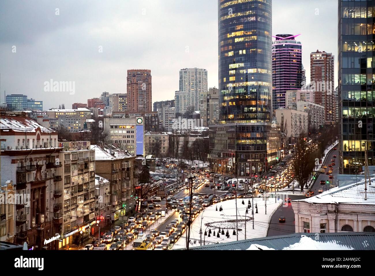 Hohe Betrachtungswinkel der Kiewer Innenstadt in Schnee und Autobahn Autoverkehr in kalten Winterabend. Alte und moderne Hochhäuser, Urban Business Konzept. Stockfoto