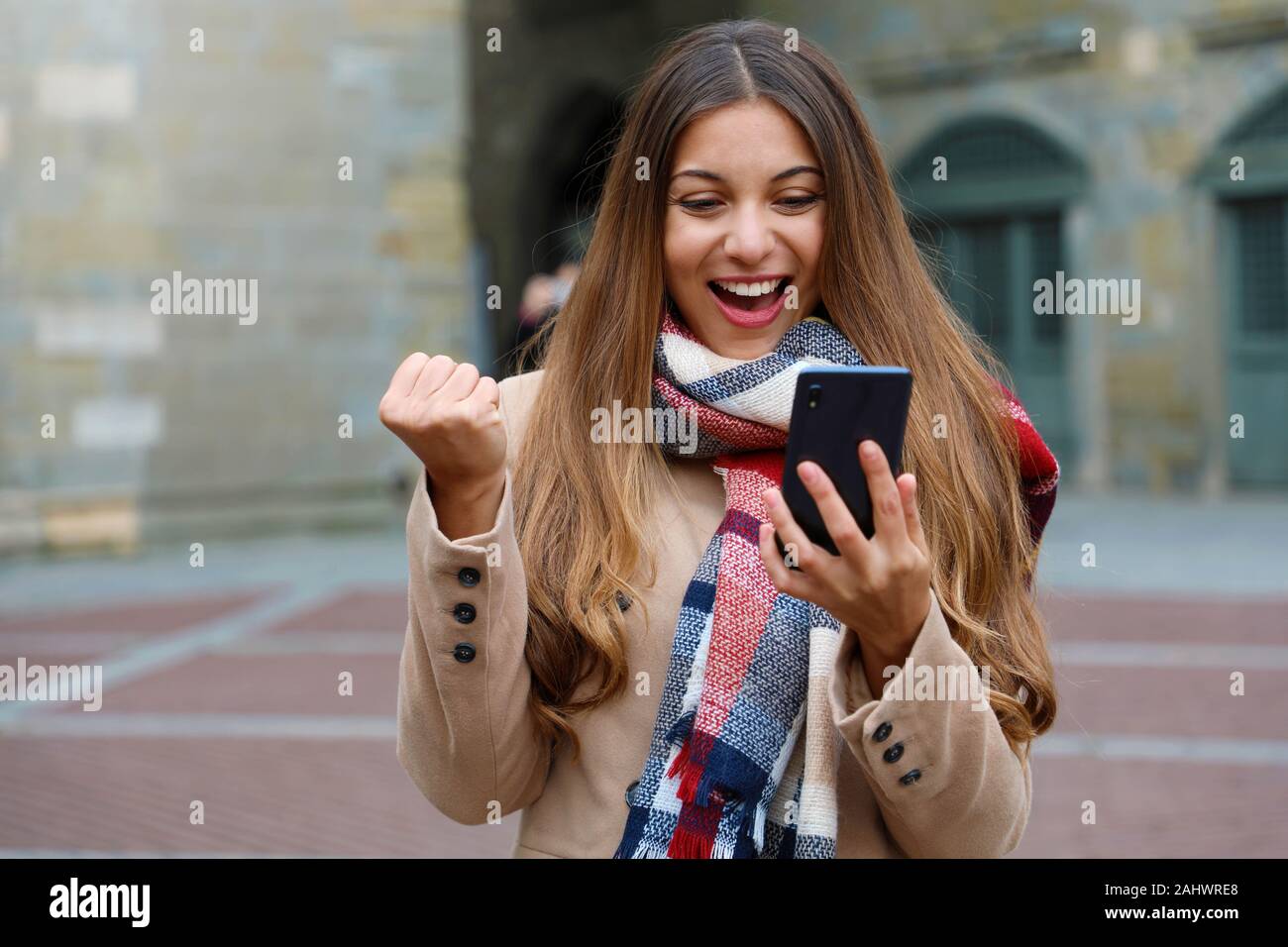 Gerne Begeistert junge Frau lacht beobachten gute Nachrichten auf Handy mit Faust in der Stadt, im Winter Stockfoto