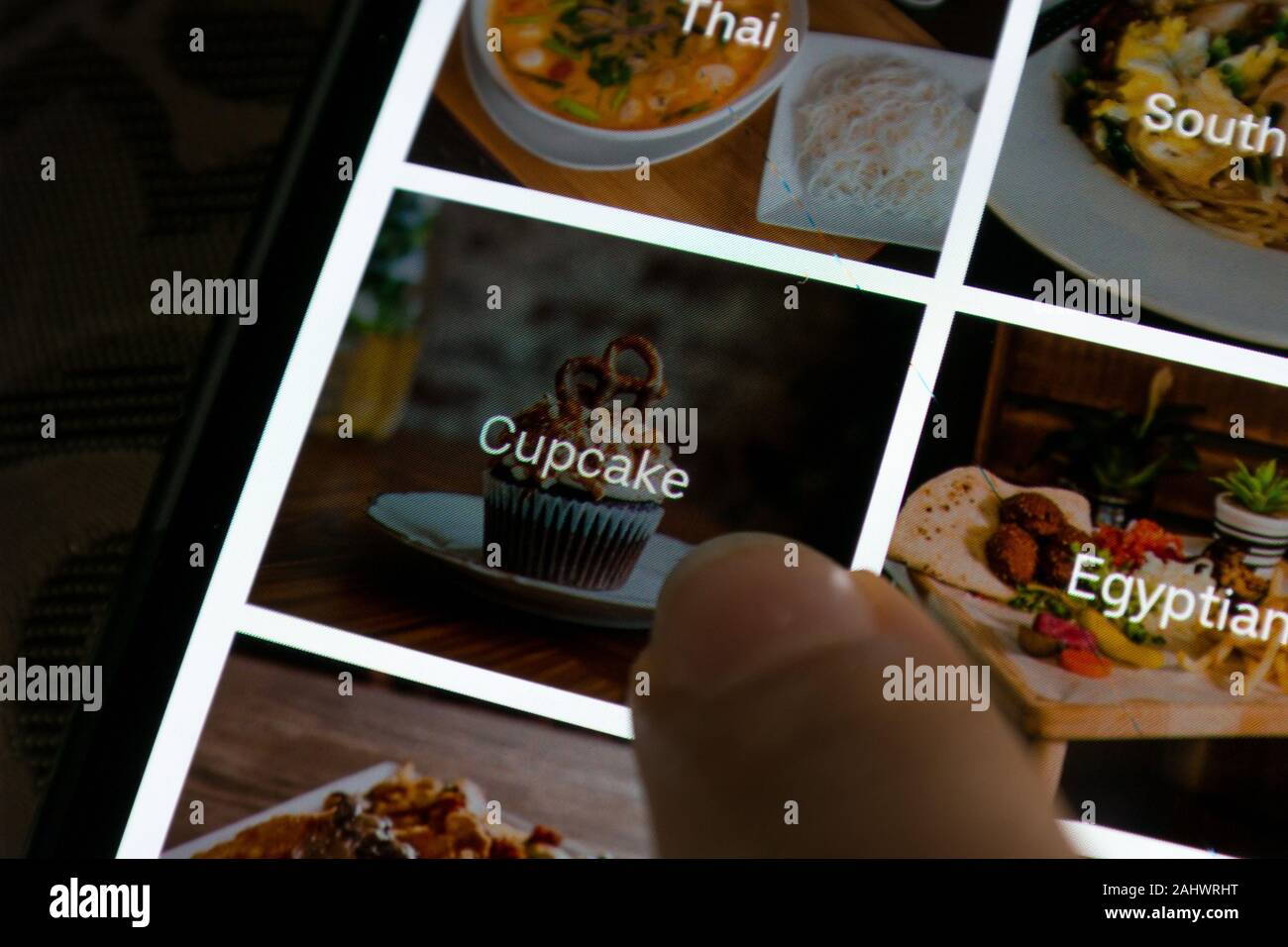Eine Person, die Cupcakes Dessert auswählt, während sie Essen online über eine App bestellt - Uber Isst die App zur Lieferung von Lebensmitteln Stockfoto