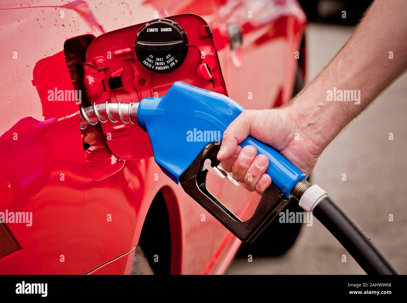 Horizontale Schuß eines Menschen Hand Benzin pumpen in ein rotes Auto. Stockfoto