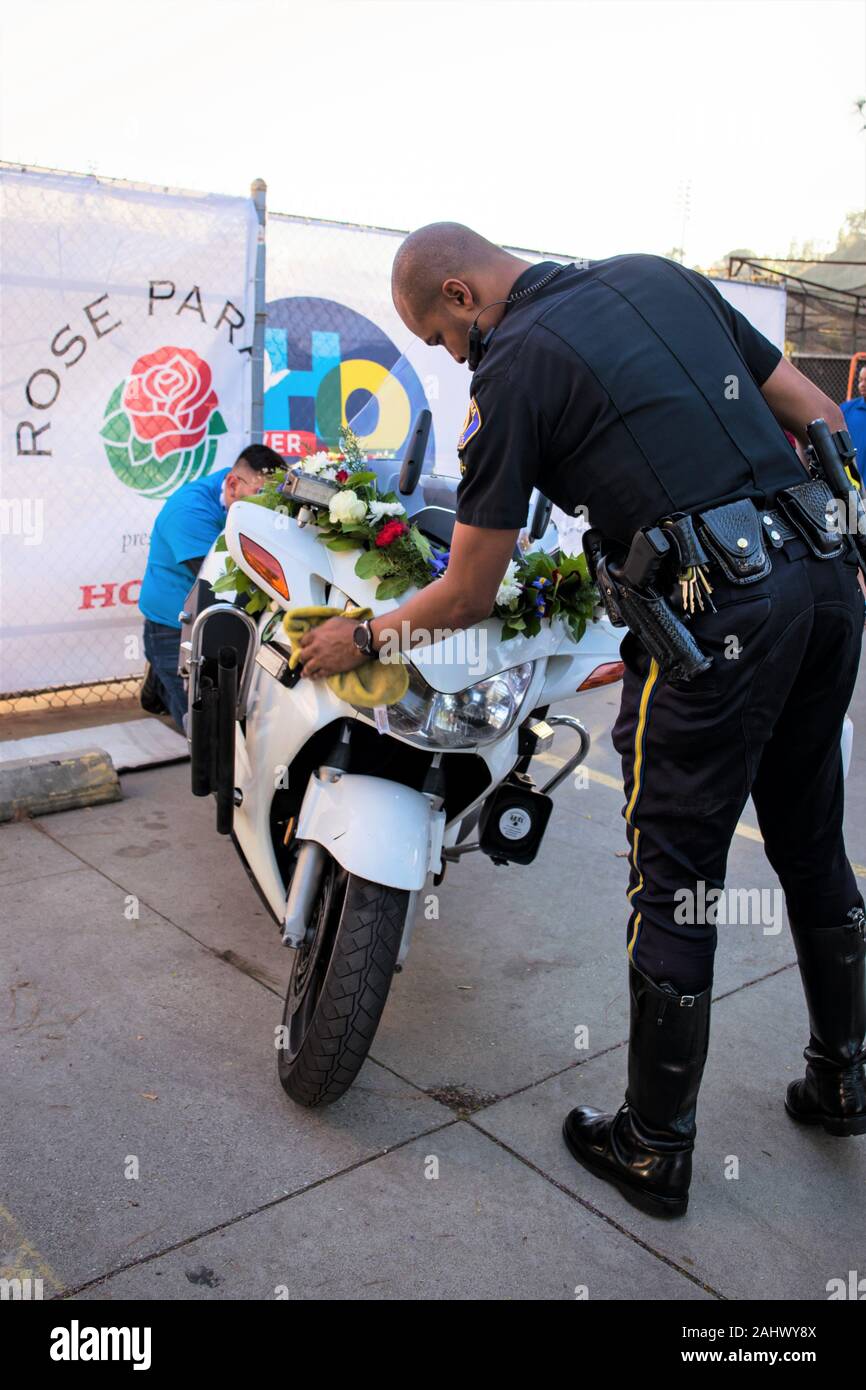 Pasadena Polizeioffizier Wischtücher motorcyclye mit einer Vielzahl von roten, weißen und blauen Kalifornien Blumen und Laub. Stockfoto