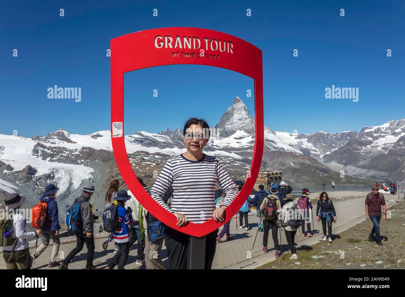 Ein chinesischer Tourist stellt für ein Bild auf einer Grand Tour der Schweiz rote Fenster mit dem Matterhorn auf der Rückseite. Gornergrat, Schweiz Stockfoto