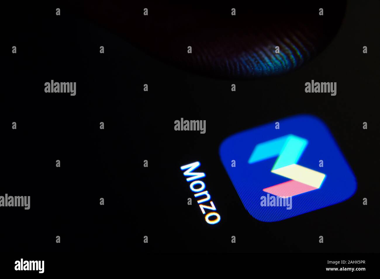 Monzo App-Symbol auf dem Smartphone-Bildschirm und Finger starten. Stockfoto