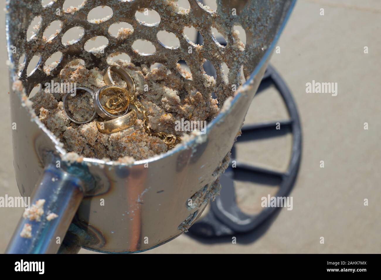 Schmuck in Strand sand Schaufeln mit Metalldetektorspule auf Sand im Hintergrund am Strand in Florida. Stockfoto