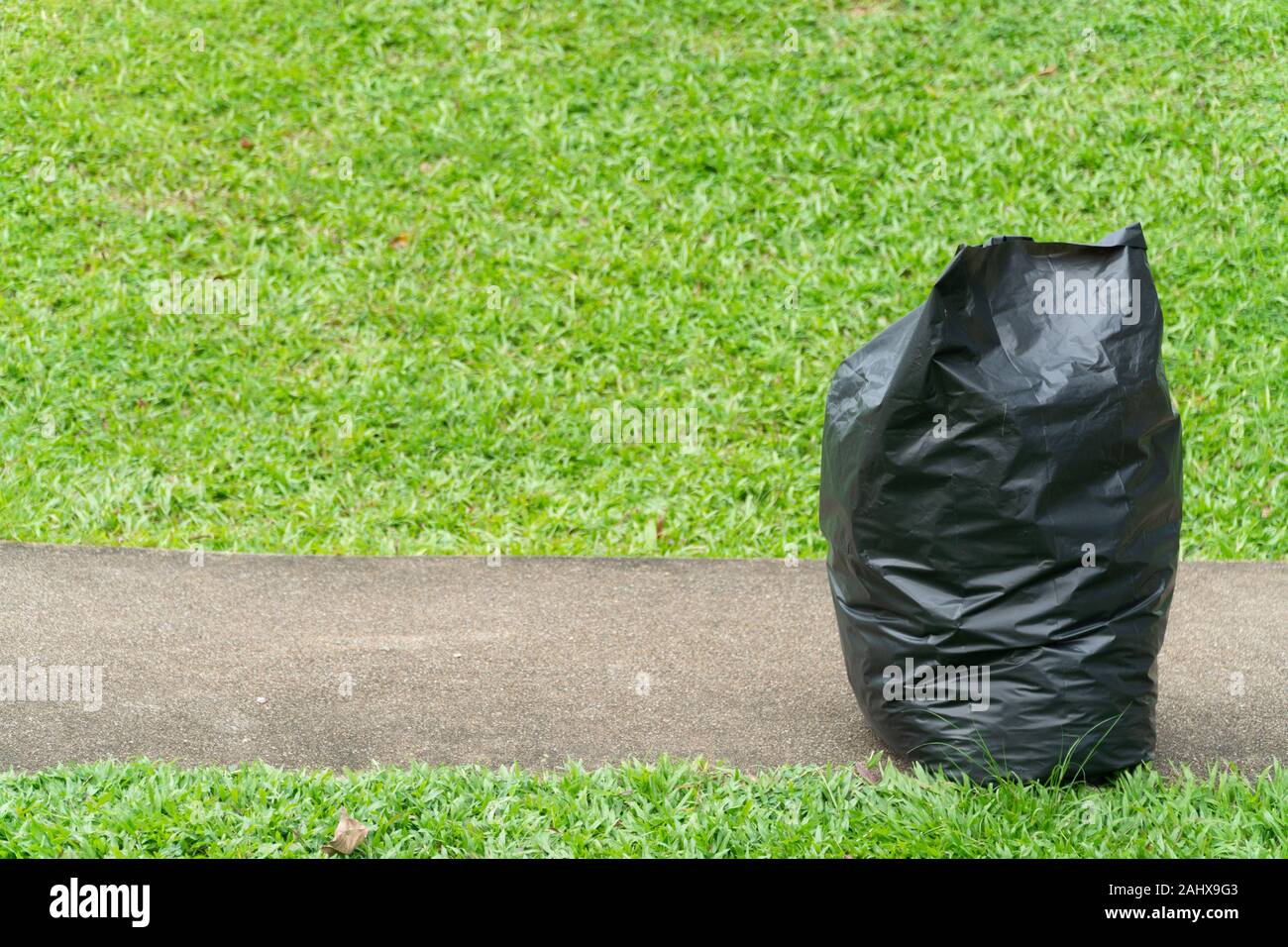 Schwarze Müllsäcke auf dem grünen Rasen in einem Park Stockfoto