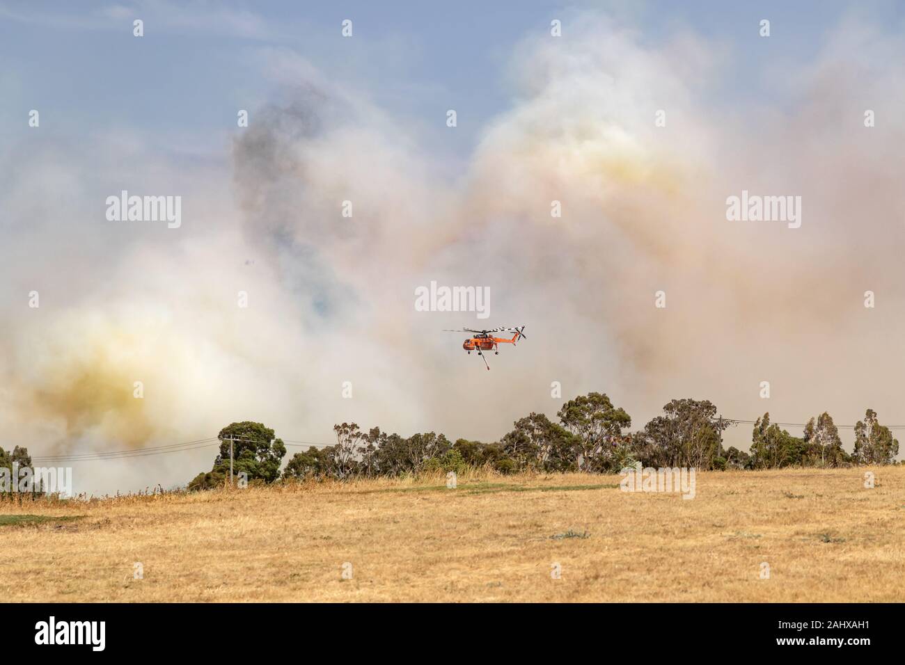 Erickson Air Crane Helikopter N 243 AC (Sikorsky S-64) gegen Federn von Rauch fliegen während dem Kampf gegen Buschfeuer in Victoria, Australien. Stockfoto