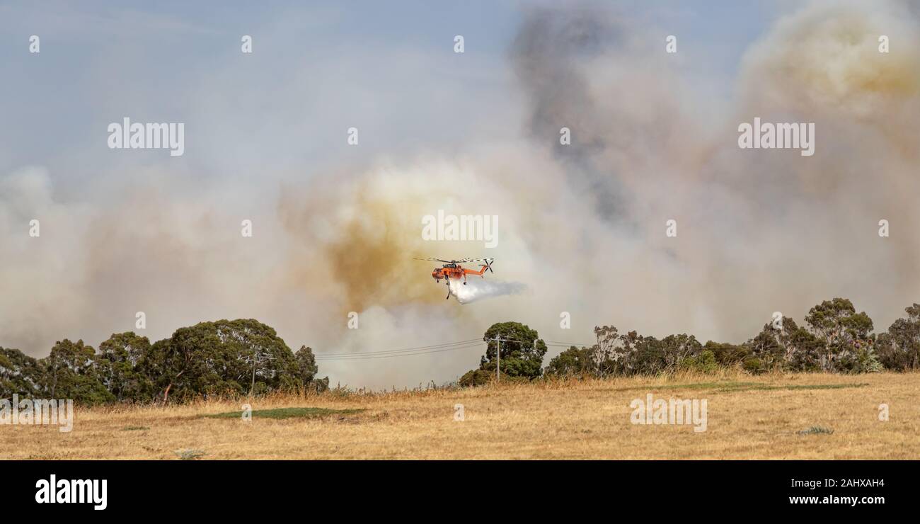 Erickson Air Crane Helikopter (Sikorsky S-64) N 243 AC fällt eine große Last von Wasser auf ein buschfeuer zur Unterstützung der Brandbekämpfung durch die Besatzungen auf. Stockfoto