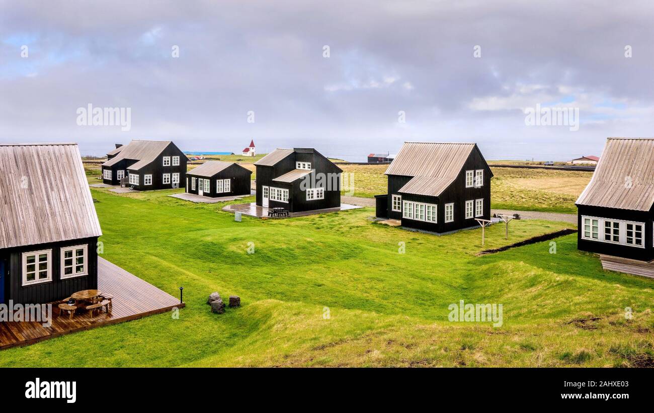 Eine kleine Gemeinschaft von schwarzen hölzernen Isländischen Ferienwohnungen, die alle das gleiche Design Elemente haben, an der Küste des Atlantischen Ozean. Stockfoto