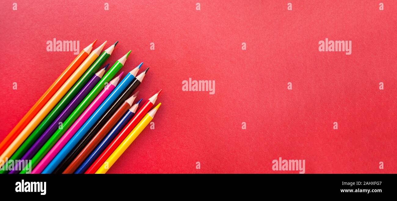 Bunte Bleistifte auf rotem Hintergrund mit Copyspace. Schule Banner. Stockfoto