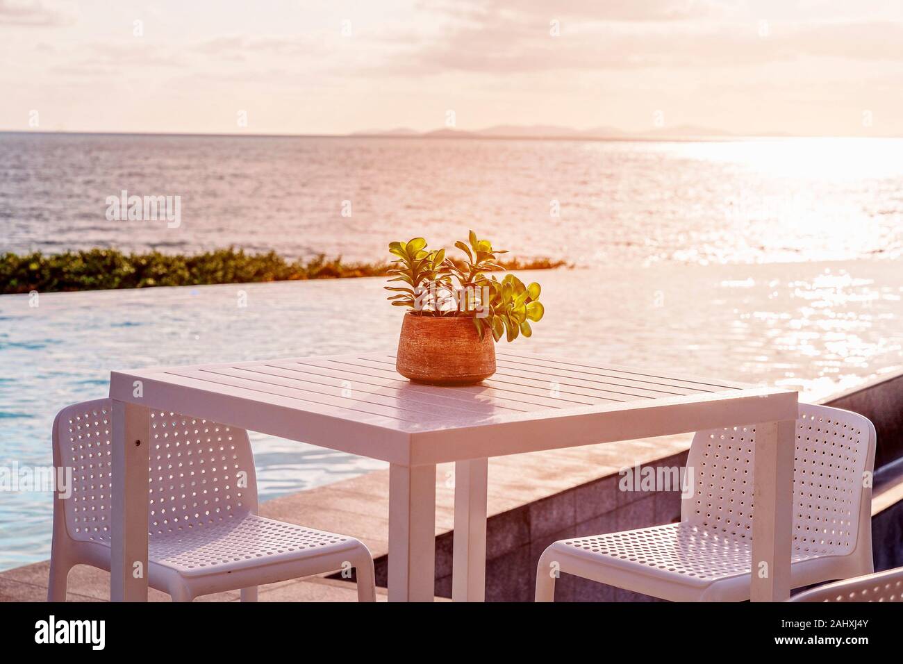 Tisch und Stühlen neben einem Infinity Edge Lagune in sanften Morgenlicht aus über dem Ozean umspült, ein friedlicher Vista in Australien Stockfoto